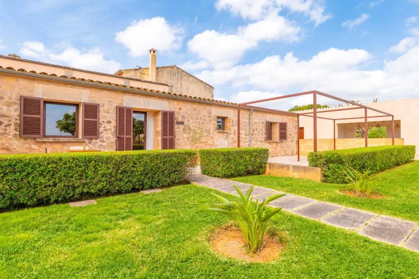 Una casa de piedra da a un césped verde con un sendero pavimentado.
