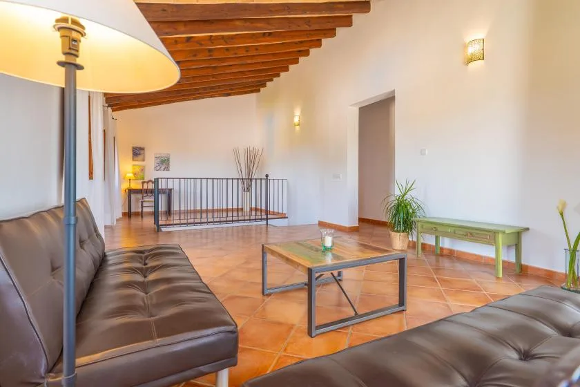 Una sala de estar con asientos, una mesa de centro y vigas de madera expuestas en el techo.