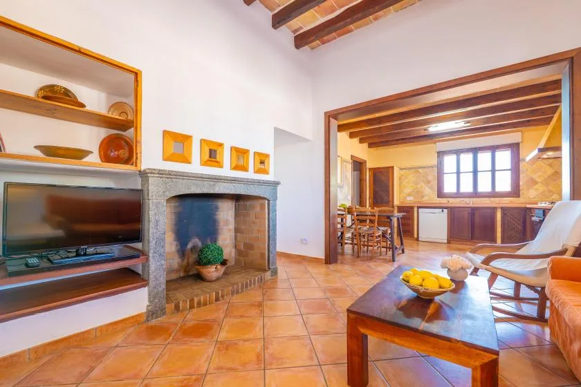 Una sala de estar se abre a una cocina, con chimenea y asientos.