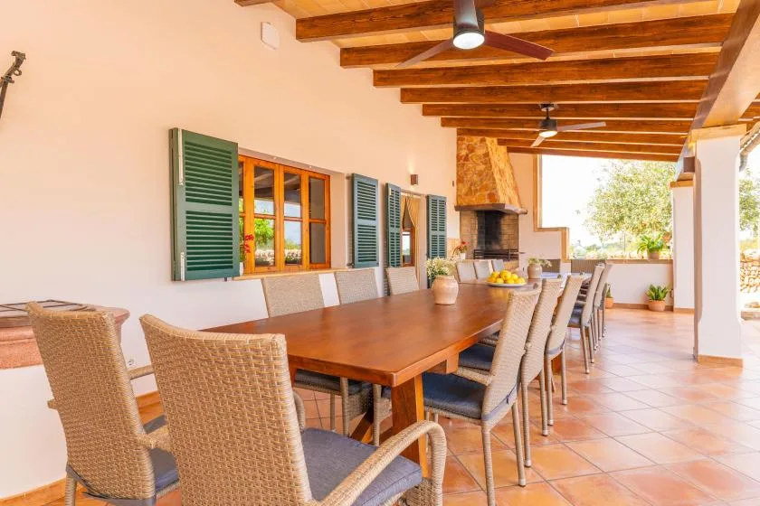 Un comedor exterior cubierto con una mesa larga y asientos tejidos.
