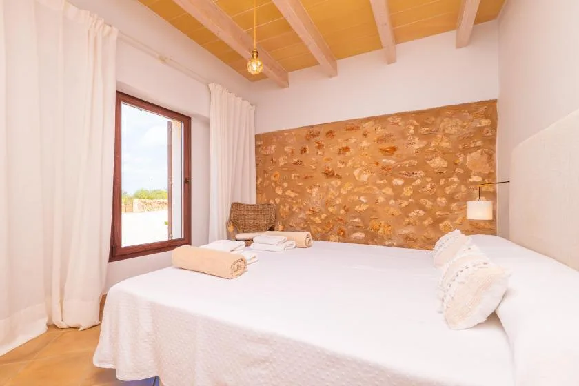 Un dormitorio con una cama grande y una pared de piedra.