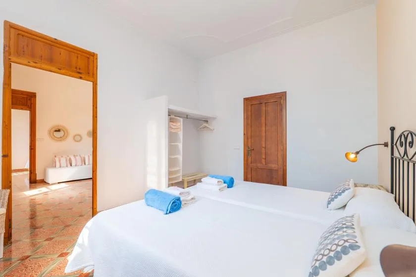 Un dormitorio con una cama bien tendida, puertas de madera y un armario abierto.