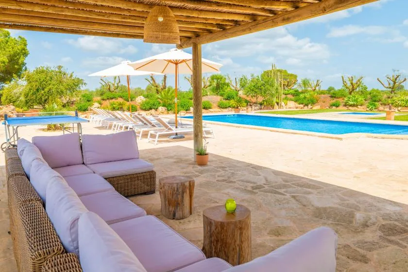 A shaded outdoor seating area overlooks a swimming pool and landscaped grounds.