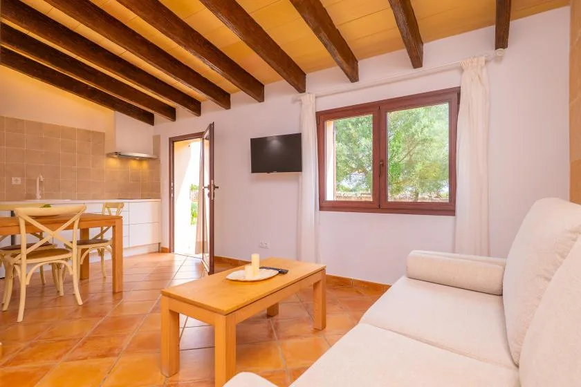 Una zona de estar y comedor con una mesa de centro de madera y una ventana luminosa.