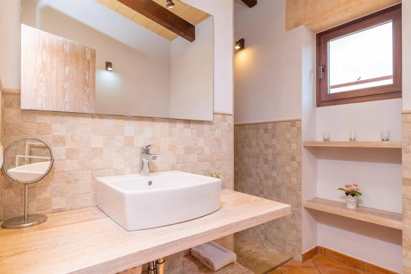 Un baño con un lavabo blanco sobre encimera debajo de un espejo grande.