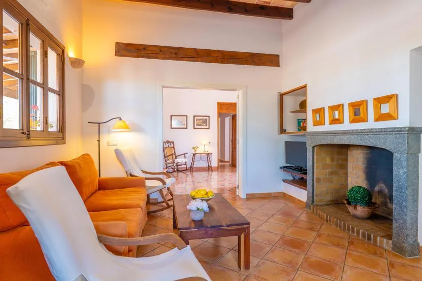 Una sala de estar con asientos naranjas, una chimenea y una mesa de centro.
