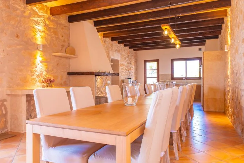 Una larga mesa de comedor con asientos tapizados bajo vigas expuestas.