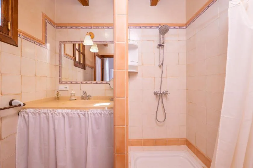 Un baño alicatado con lavabo, espejo y ducha.