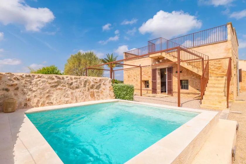 Una piscina está junto a un edificio de piedra con una escalera exterior.