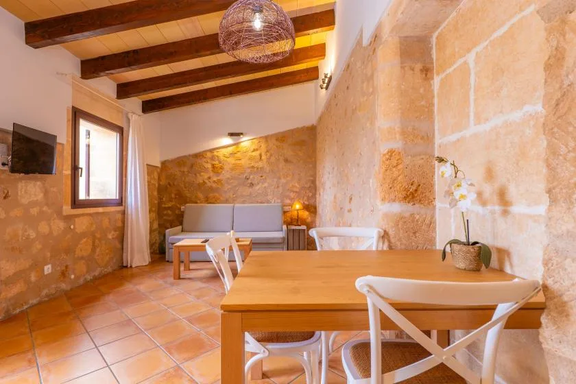 Una sala de estar y comedor rústica con mesa de madera y asientos.