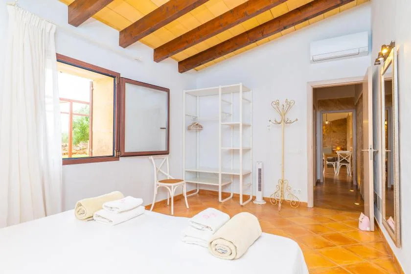 Un dormitorio con cama, estantería abierta y vigas de madera a la vista.