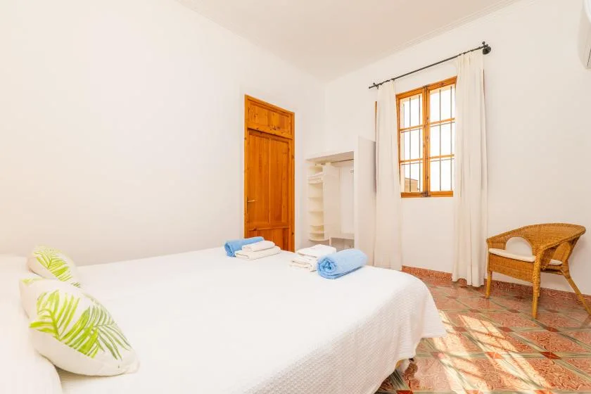 Un dormitorio luminoso con una cama, una puerta de madera y una ventana soleada.
