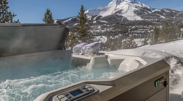 Una bañera de hidromasaje al aire libre burbujea bajo una montaña nevada.