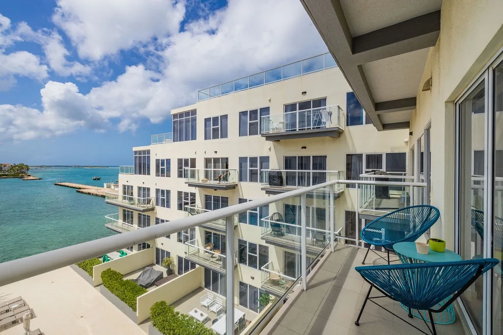 Modern waterfront property featuring multiple balconies with glass railings
