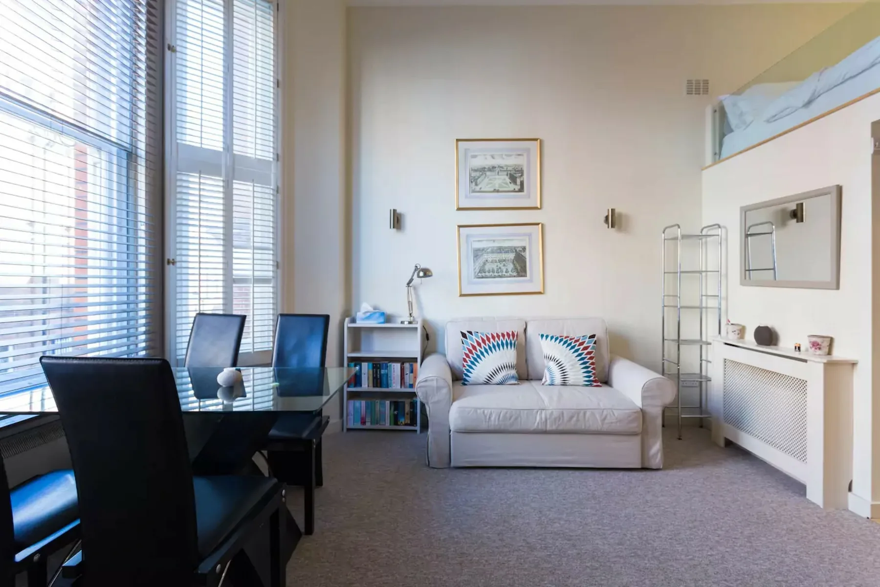 A bright sitting room with a small sofa beside tall windows.