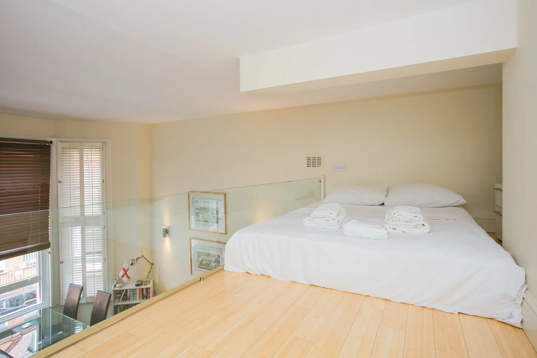 A bright bedroom with a white bed and large windows.