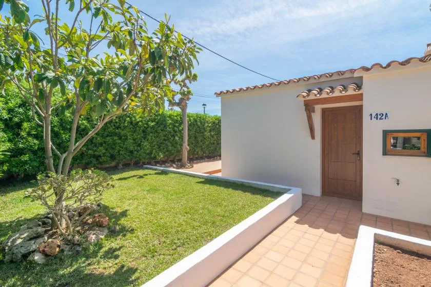 A small landscaped courtyard with a tiled walkway leading to a wooden door.
