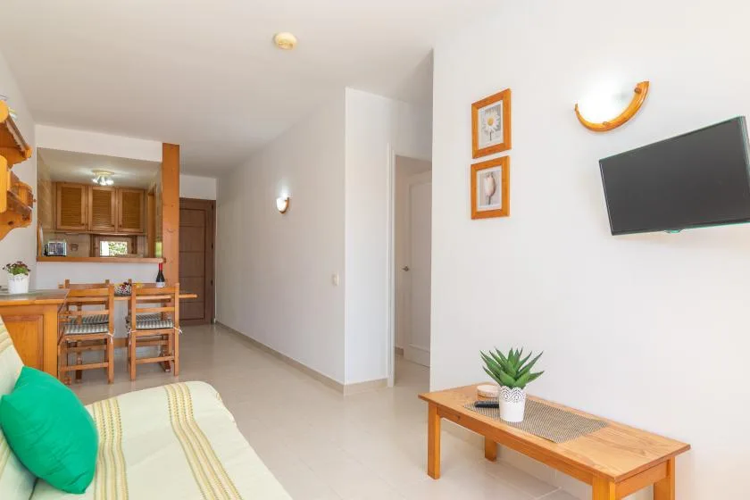 A bright living room with a dining area and a wall-mounted television.