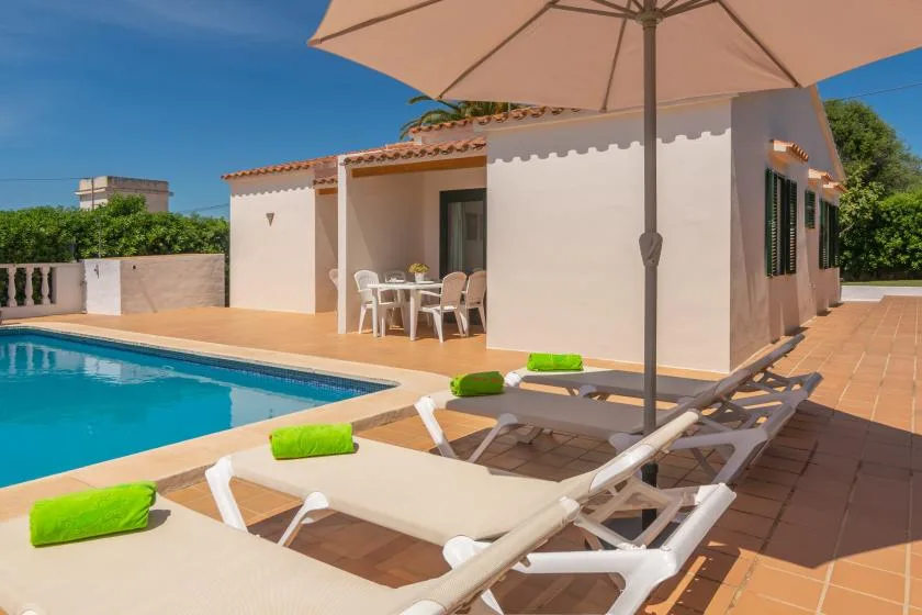 A poolside patio with lounge seating beside a white building.
