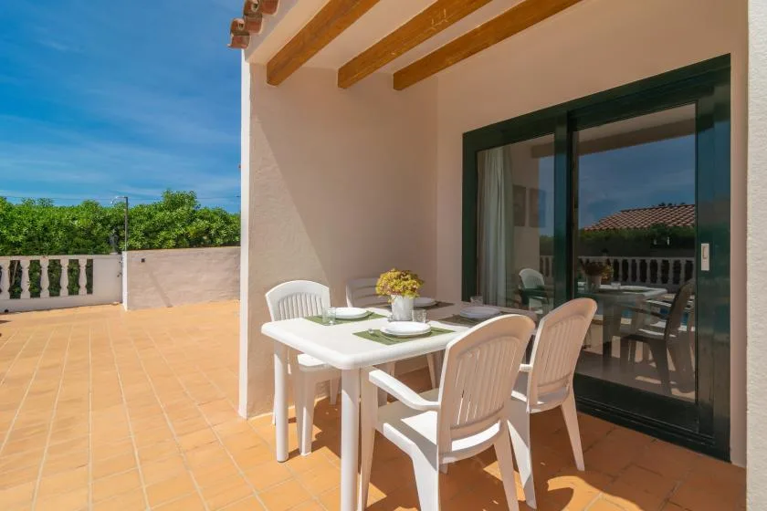 A tiled outdoor terrace with a dining table and sliding glass doors.