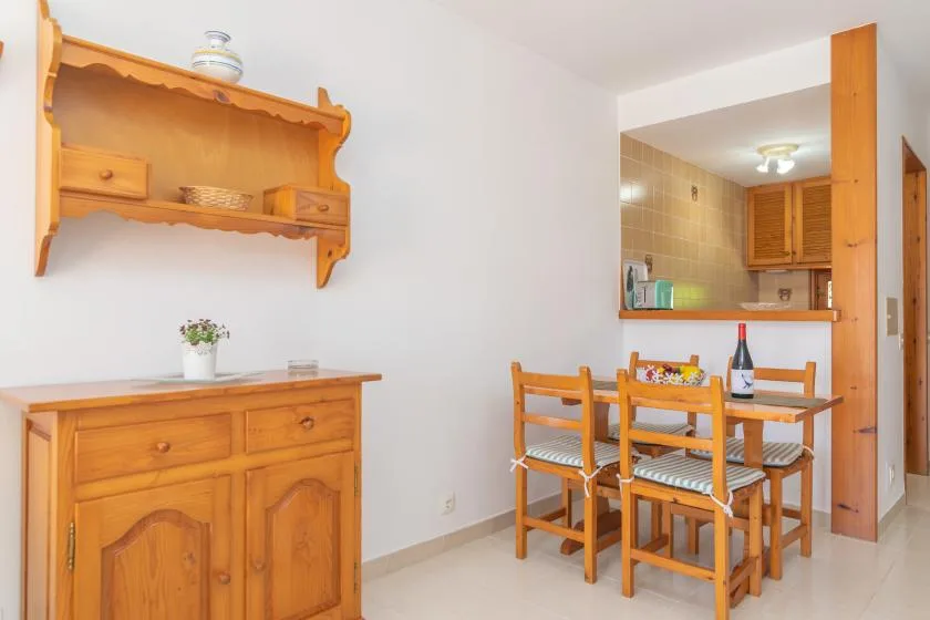 A dining area with wooden seating beside a kitchen pass-through.