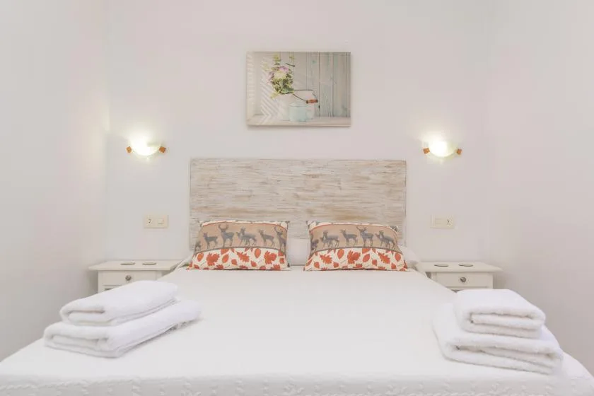 A bright bedroom with a bed, patterned pillows, and matching bedside tables.