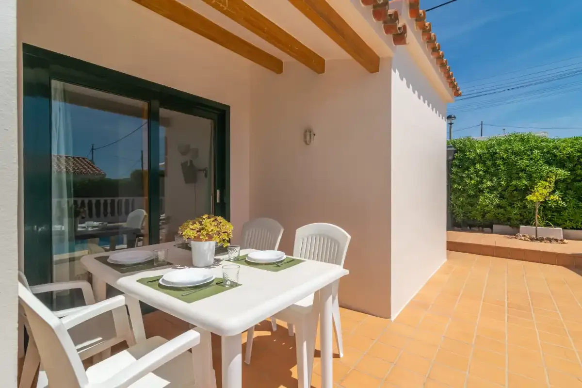An outdoor dining area with a table and chairs beside a sliding glass door.