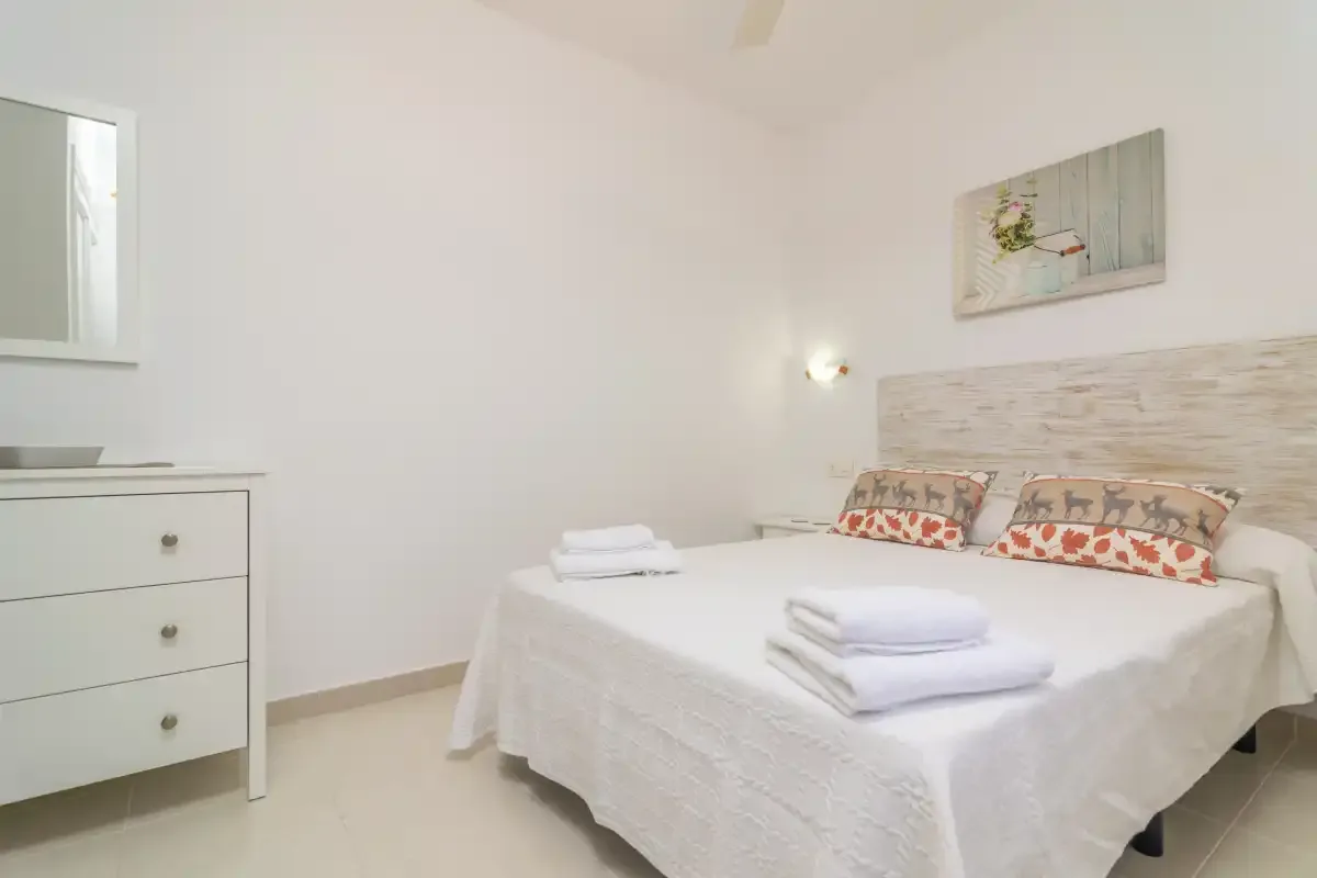 A bright bedroom with a neatly made bed and folded towels.