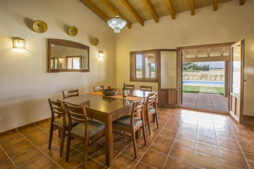 Un comedor con mesa y sillas de madera da a una terraza.