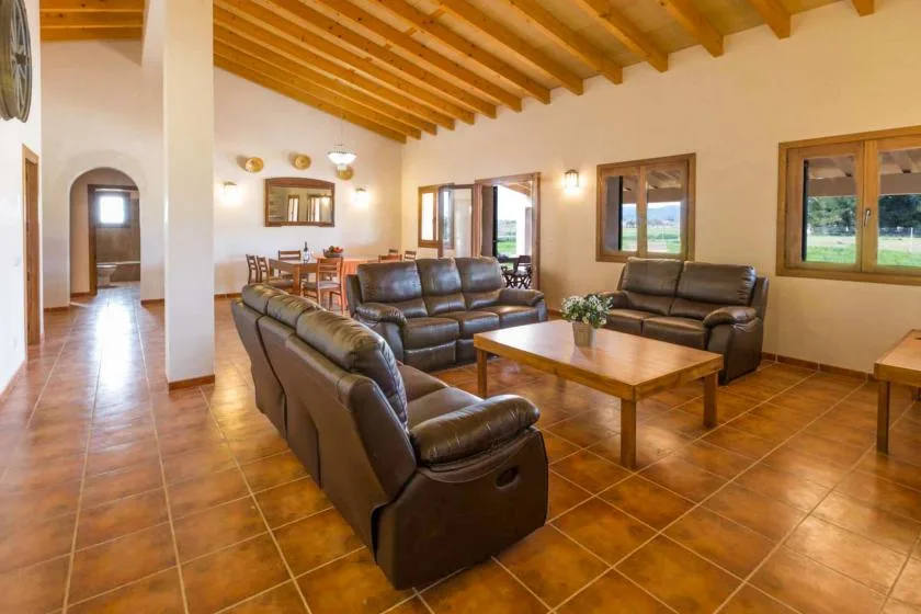 Una sala de estar con asientos de cuero, una mesa de centro de madera y ventanas.
