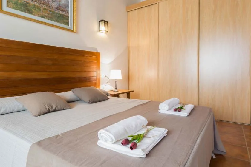 Un dormitorio con una cama bien hecha y toallas dobladas.