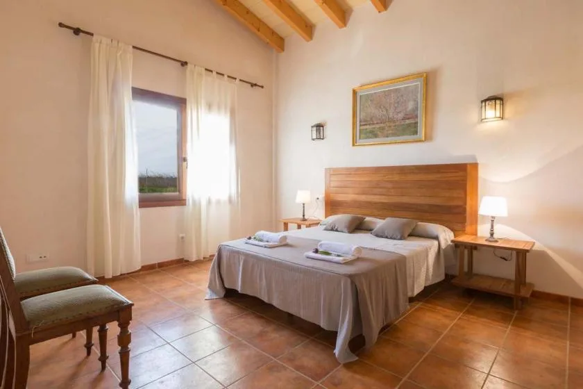 Un dormitorio con una cama doble, mesitas de noche y una ventana con cortinas.