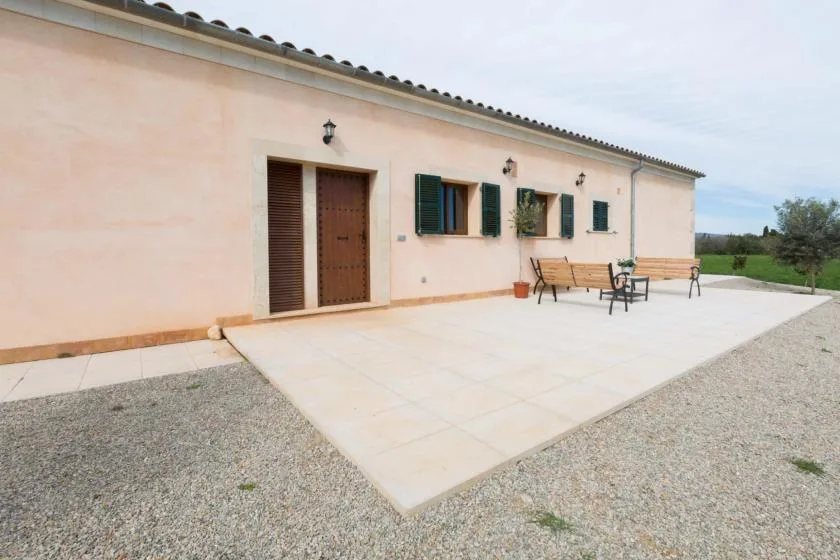 Un edificio de estuco claro da a un amplio patio pavimentado con asientos al aire libre.