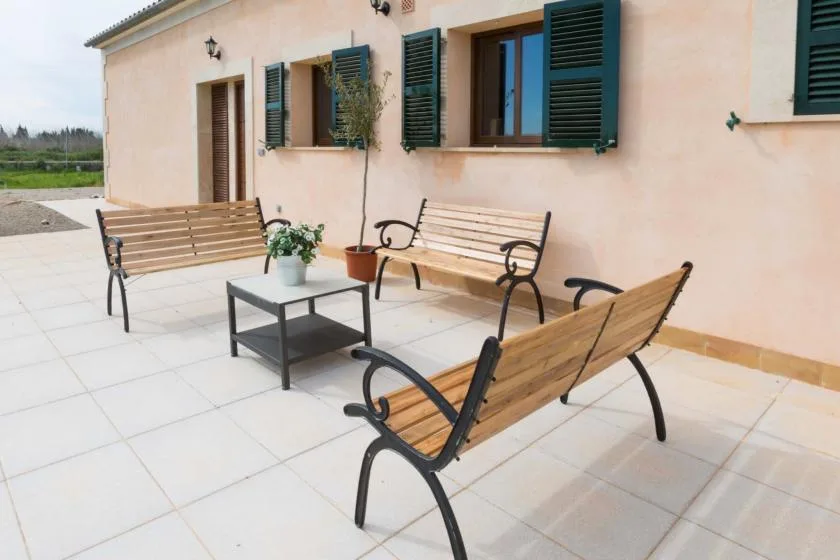 Un patio pavimentado con bancos de madera y una mesa pequeña junto a un edificio.