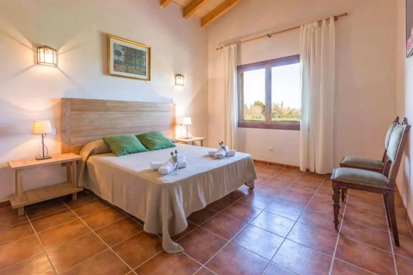 Un dormitorio con una cama, mesitas de noche y una ventana con cortinas.