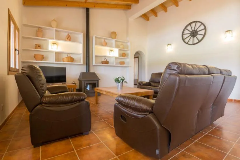 Sala de estar con asientos de cuero, una mesa de centro y un televisor.