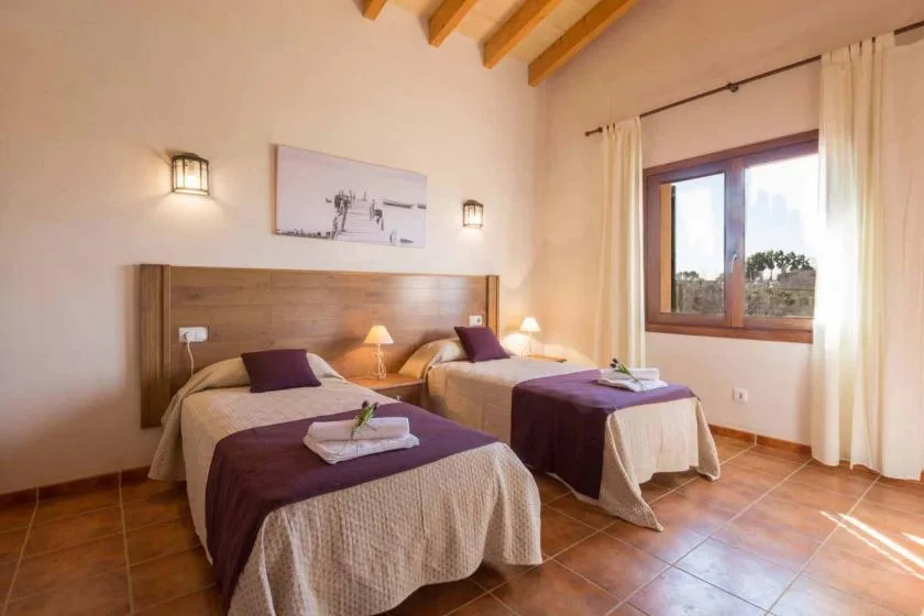 Un dormitorio con dos camas, lámparas de noche y una ventana.