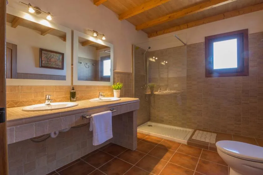 Un baño con lavabo doble y una ducha con mampara de vidrio.