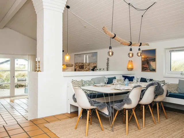 A dining area with a table and chairs beneath hanging lights.