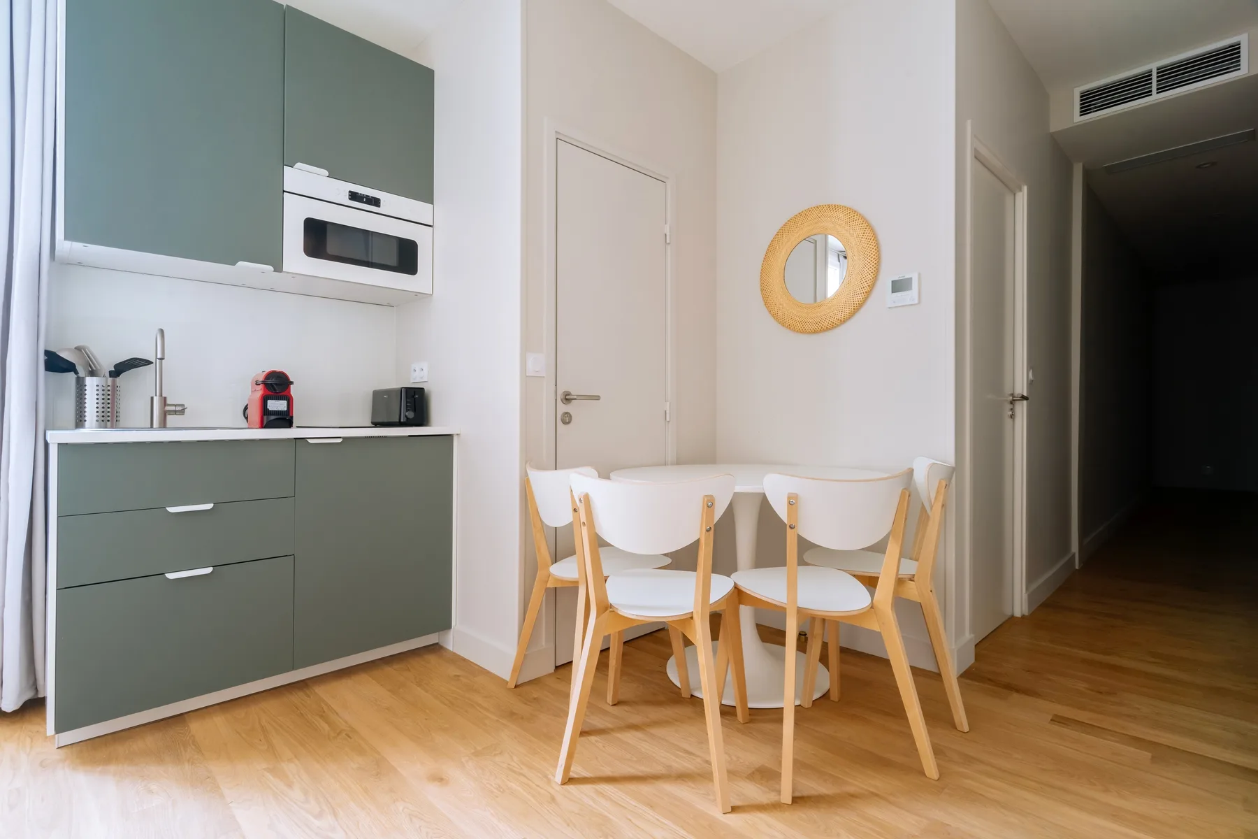 A compact kitchen and dining area with a table and light-colored seating.