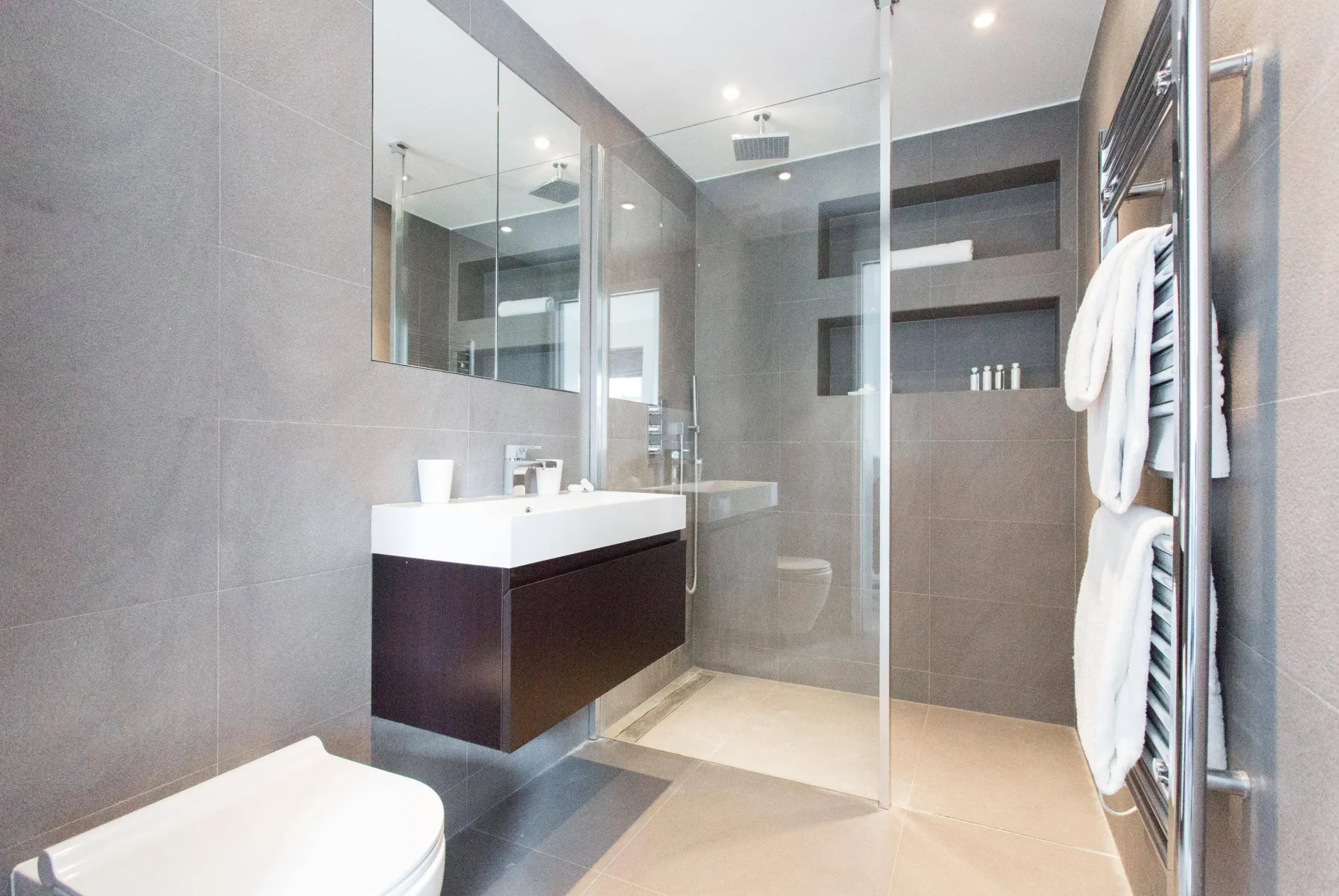 Un baño moderno con un lavabo flotante y una ducha de cristal.