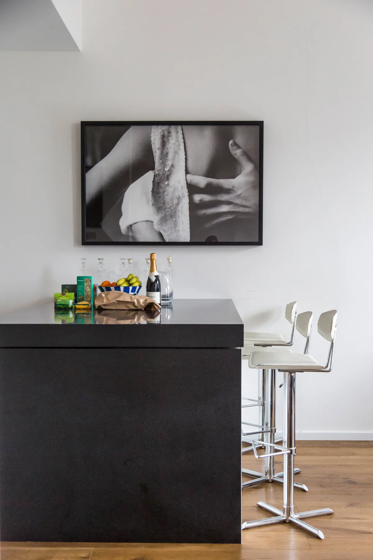 Una barra de cocina moderna con asientos altos y una fotografía enmarcada en blanco y negro.
