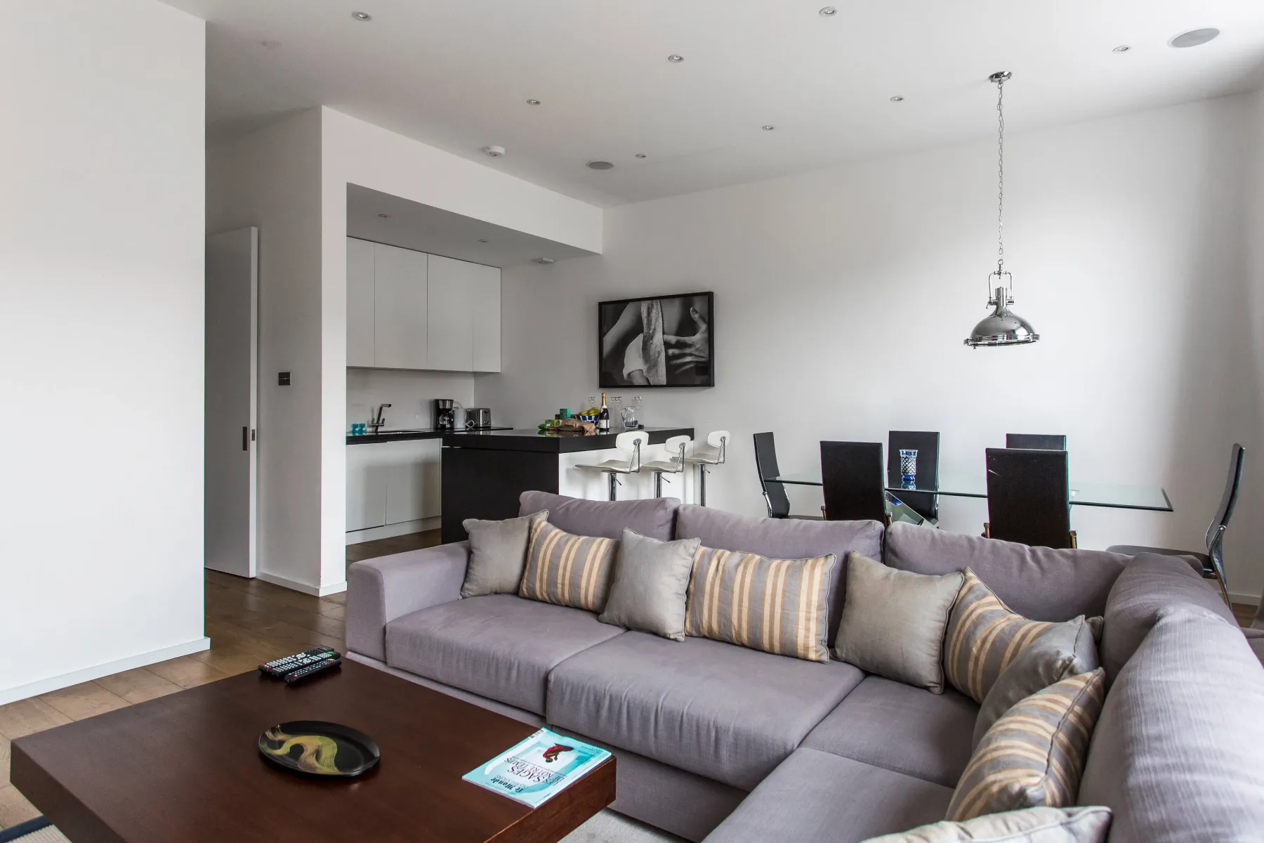 Sala-comedor de planta abierta con un sofá seccional gris y cocina.