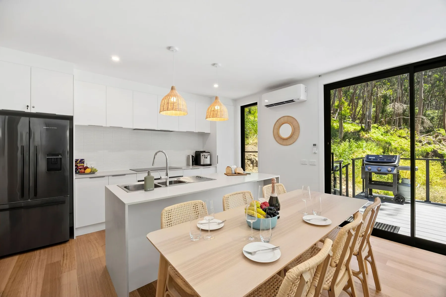 Una cocina y comedor luminosos se abren a una terraza exterior frondosa.