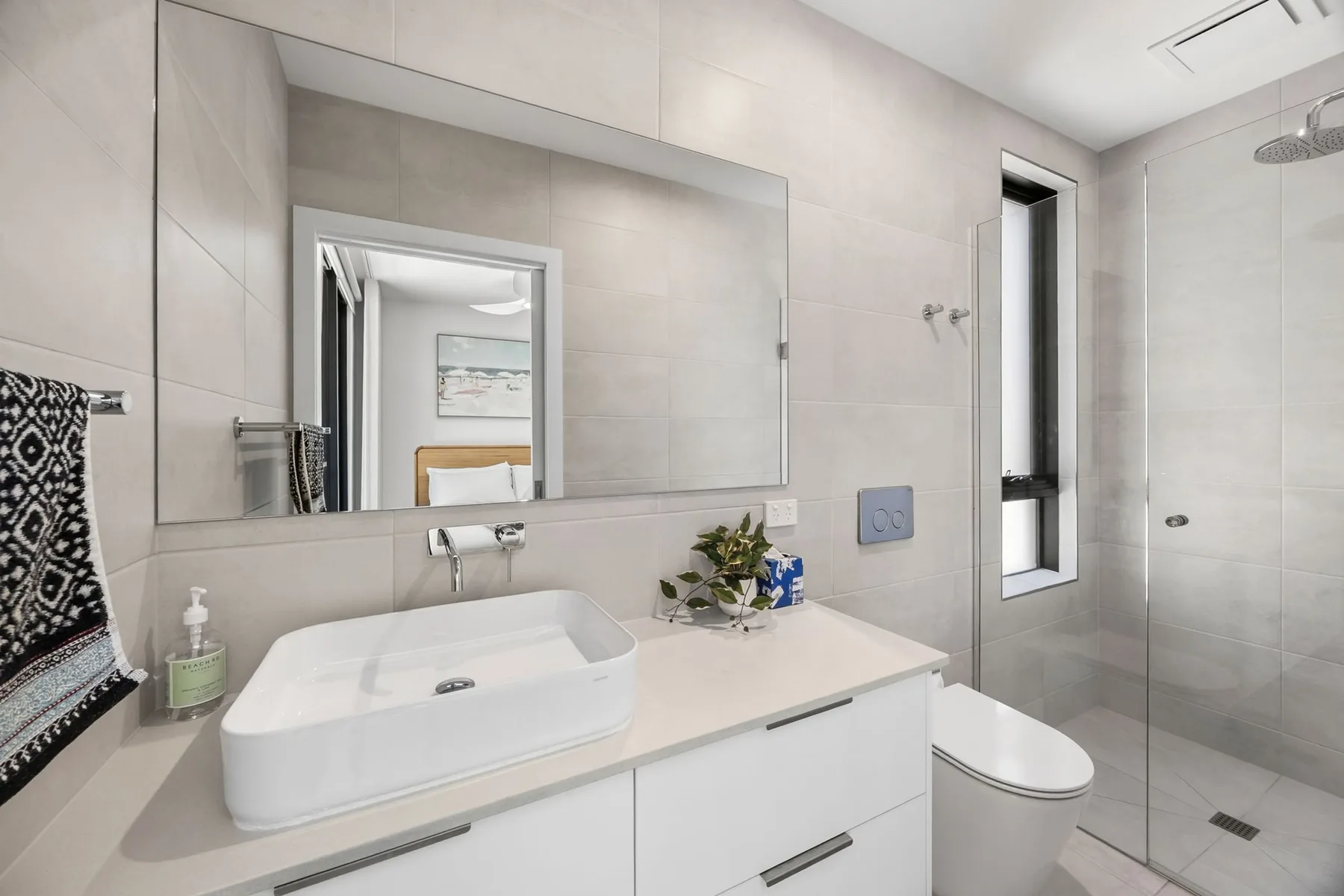 Un baño luminoso con lavabo, inodoro y ducha con mampara de vidrio.