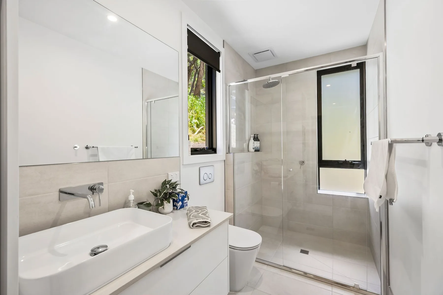 Un baño luminoso con lavabo, inodoro y ducha de vidrio.