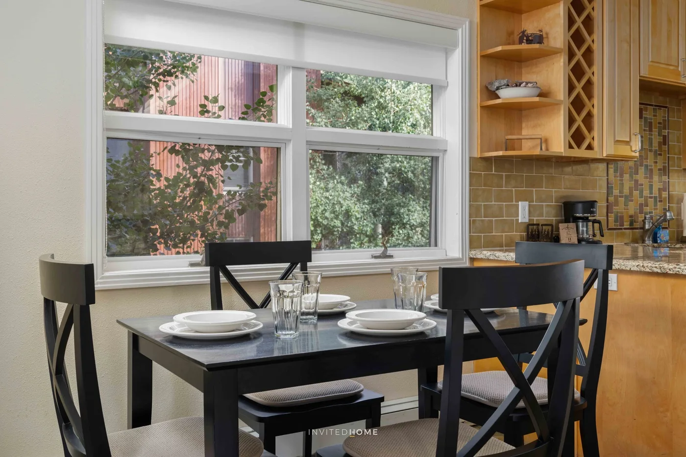Un comedor con una mesa oscura y sillas junto a una ventana grande.