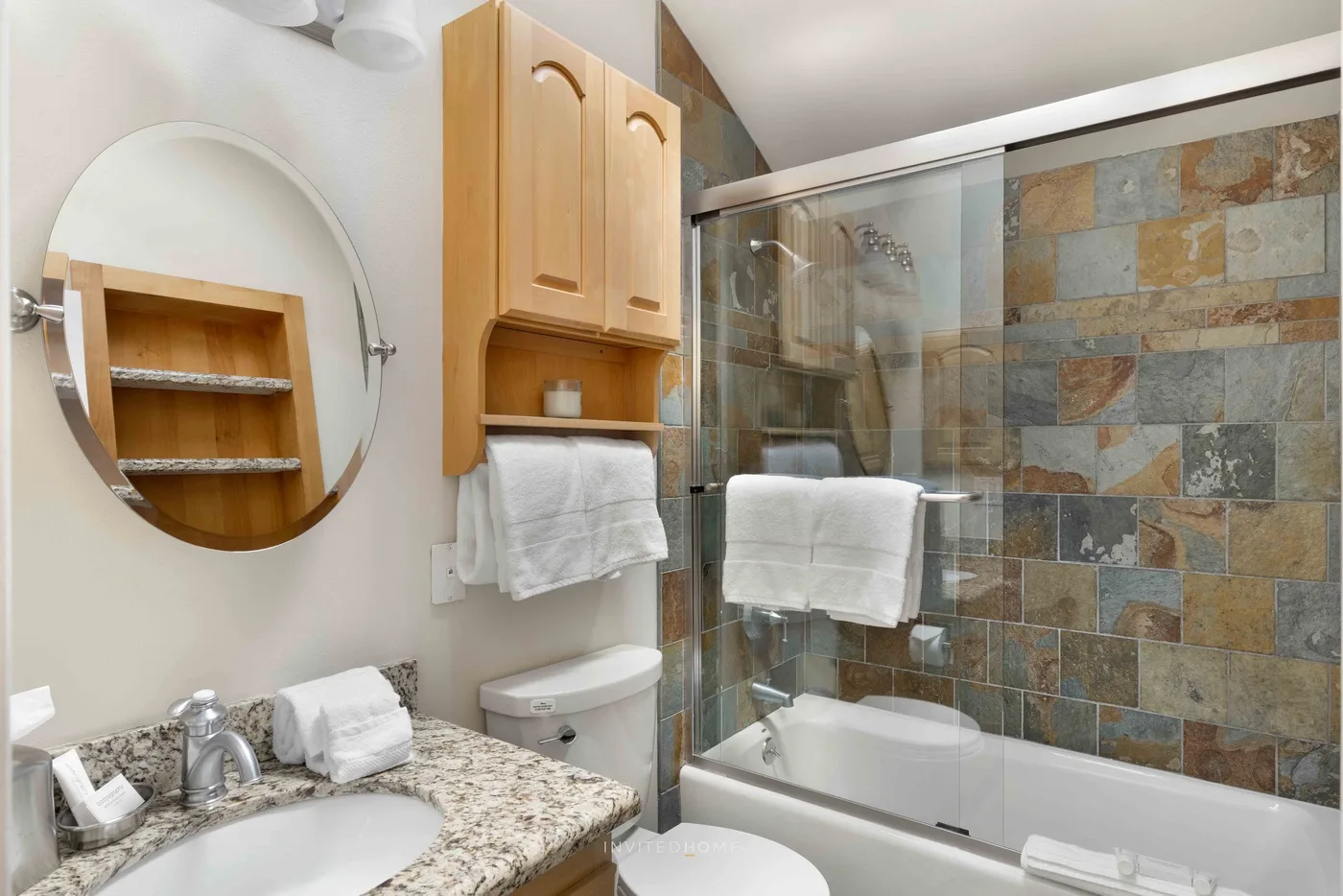 Un baño con bañera y mampara de vidrio junto a una pared de azulejos.