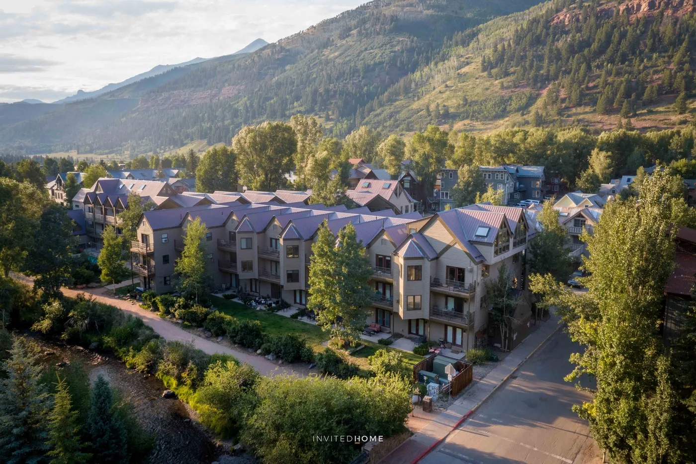 Un barrio residencial con casas agrupadas se encuentra al pie de una montaña boscosa.