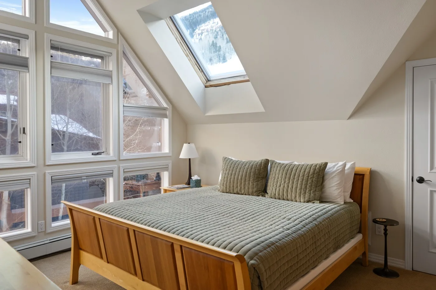 Un dormitorio con una cama de madera bajo un techo inclinado y una claraboya.